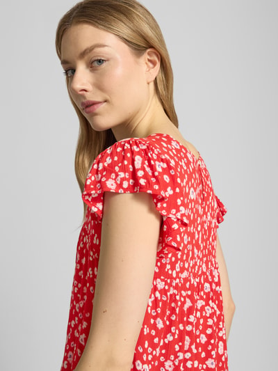 Modelka nosi Blusenshirt aus Viskose Modell 'MARRAKECH' od ICHI, krój regular fit, wzór allover, dekolt w serek, czerwony z białymi kwiatami, widok na górną część ciała z przodu