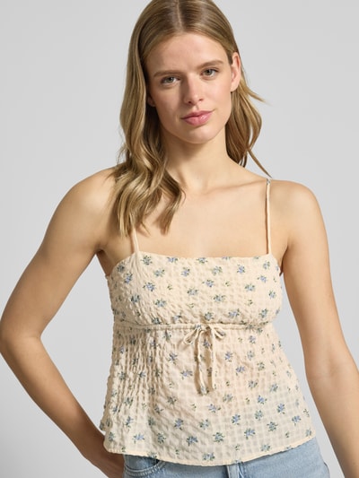 Frauenmodel trägt Babydoll-Top aus Seersucker mit Schnürung von REVIEW, Regular-Fit, Strukturmuster, verstellbare Spaghettiträger, zartes Beige mit kleinen blauen Blumen, Material-Mix mit Stretch-Anteil, Rückenlänge bei Größe S: 29 cm, Ganzkörperansicht von vorne.