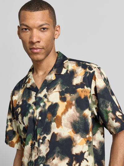 Männermodel trägt Relaxed Fit Freizeithemd aus Bio-Baumwoll-Modal-Mix Modell 'RELAXAIR' von SELECTED HOMME, Optik: Unifarben, Passform: Relaxed Fit, Hemdkragen: Reverskragen, Knopfleiste: durchgehend, Ärmelform: Kurzarm, Material: Bio-Baumwoll-Modal-Mix, bunte abstrakte Farbmuster, Nahaufnahme Oberkörper.