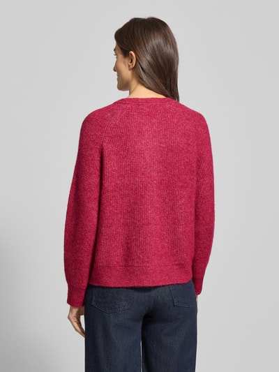 Vrouwenmodel draagt Regular Fit Strickjacke aus Woll-Mix mit Alpaka-Anteil Modell 'LULU' van Selected Femme, effen rood, gebreide textuur, lange raglanmouwen, rugaanzicht.