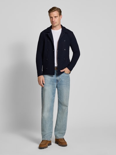 Männermodel trägt Slim Fit Cardigan mit Leinen-Alpaka-Anteil in Strick-Optik von Manuel Ritz, dunkelblau, Umlegekragen, doppelte Knopfleiste, Material-Mix, Jeans und braune Schuhe, Ganzkörperansicht von vorne.