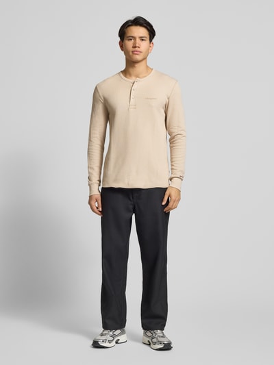 Męski model nosi Regular Fit Langarmshirt aus reiner Baumwolle od Tommy Jeans, efekt: jednolity kolor, faktura, z napisem z logo, okrągły dekolt, długi rękaw, zakończenia rękawów elastyczne, bawełna, Ganzkörperansicht von vorne.