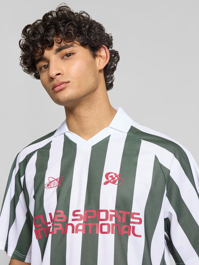 Männermodel trägt Loose Fit Poloshirt mit Motiv-Print Modell 'ZIDAN' von Only & Sons, grün-weiß gestreift, Piqué, Nahaufnahme Oberkörper.