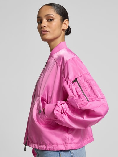 Frauenmodel trägt Boxy Fit Jacke mit Zweiwege-Reißverschluss Modell 'JODY' von Beaumont Amsterdam in kräftigem Pink, Nahaufnahme Oberkörper. Damenjacke mit Stehkragen, Eingrifftaschen mit Druckknopfverschluss, sichtbare Textur und glänzende Oberfläche, Kontext: mittlere Rückenlänge und lockere Passform.