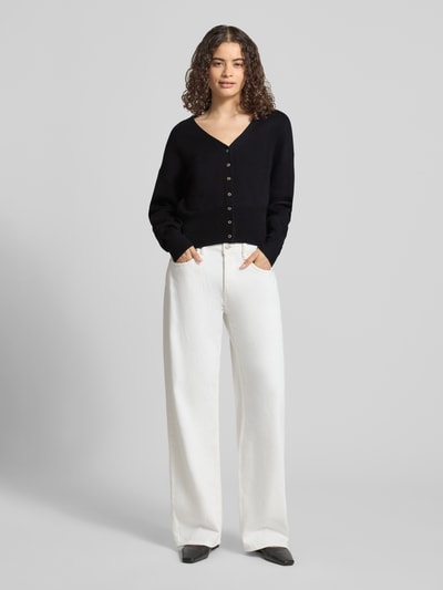 Kobiece model nosi kardigan z mieszanki bawełny i wiskozy o kroju regular fit, model 'Compact' od Topshop, imitacja dzianiny, czarny, długość tyłu 50 cm, długi rękaw 55 cm, dekolt w serek, widok całej sylwetki z przodu.