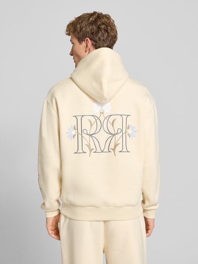 Männermodel trägt Relaxed Fit Hoodie mit Känguru-Tasche von REVIEW in Creme mit floraler Stickerei, Rückenlänge 66 cm, Ganzkörperansicht Rückansicht.