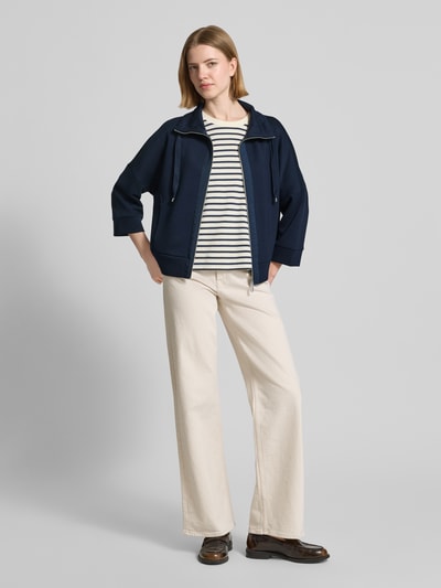 Modelka nosi Regular Fit Sweatjacke mit Viskose-Anteil od Tom Tailor, granatowa, gładka, suwak, 3/4 rękaw, krój regular fit, stehkraag, kieszenie boczne, materiał scuba, widok całej sylwetki z przodu