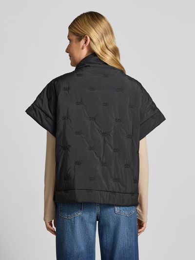 Vrouwenmodel draagt Cape met Reißverschluss en Eingrifftaschen Modell 'NETTI' van Cph Muse in zwart met opstaande kraag en regular fit, rechte vormen en gladde textuur, context: damescape, lengte achterkant maat S/M 61 cm, borstwijdte S/M 64 cm, volledig zicht van achteren.