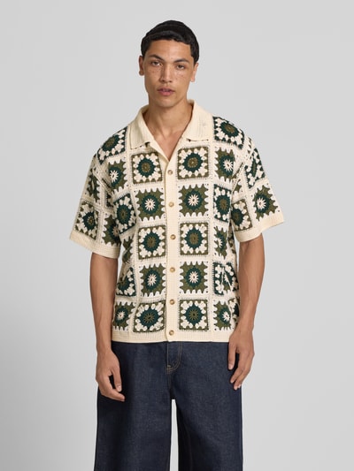 Männermodel trägt Regular Fit Freizeithemd im Allover-Look Modell 'FABIAN' von Redefined Rebel mit Polokragen und Knopfleiste, Ganzkörperansicht von vorne. Rückenlänge bei Größe M: 70 cm, Schulterbreite bei Größe M: 43 cm, Ärmellänge bei Größe M: 28 cm. Farbe creme mit grünem Muster, strukturierte, gehäkelte Optik.