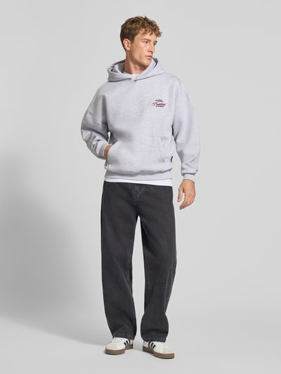 Männermodel trägt Relaxed Fit Hoodie aus Baumwoll-Mix mit Label-Stitching von PROHIBITED, grau, breite Form, Känguru-Tasche, Ganzkörperansicht von vorne.