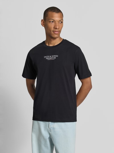 Männermodel trägt T-Shirt mit Label-Print und Rundhalsausschnitt von JACK & JONES in Schwarz, reine Baumwolle, Regular Fit, Ganzkörperansicht von vorne.