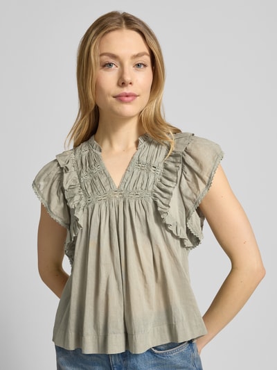 Frauenmodel trägt Bluse mit Volants Modell 'Jayla' von Neo Noir aus reiner Baumwolle in hellem Grün, lockerer Schnitt, Nahaufnahme Oberkörper.