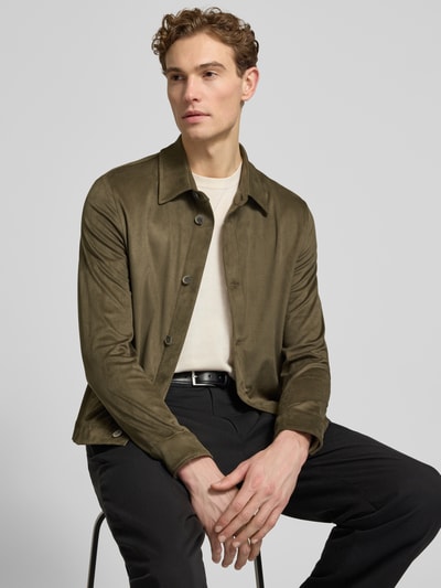Mężczyznę model nosi Regular Fit Hemdjacke mit Kentkragen Modell 'TOTO' von CINQUE, mieszanka materiałów z dodatkiem streczu, krój regular fit, długość tyłu w rozmiarze M: 67 cm, kolor oliwkowy, matowa tekstura, gładka powierzchnia, listwa guzikowa, Ganzkörperansicht von vorne.