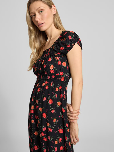 Frauenmodel trägt Midikleid aus Viskose mit Karree-Ausschnitt von Apricot, schwarze Basis mit rotem Blumenmuster, Nahaufnahme Oberkörper.