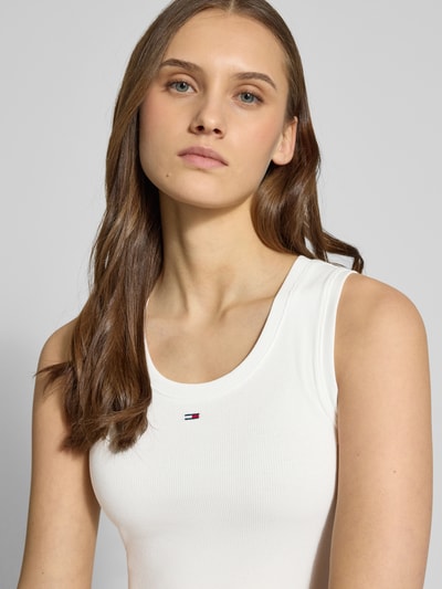 Vrouwenmodel draagt 'Slim Fit Tank Top aus Baumwoll-Mix' van Tommy Jeans, effen kleuren, slim fit, fijnrib katoenmix, logodetail, U-hals, brede bandjes, detailopname bovenlichaam.