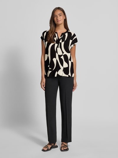 Frauenmodel trägt Regular Fit Bluse aus Viskose mit V-Ausschnitt Modell 'CHANISE' von Soyaconcept im schwarz-weißen Allover-Look, Ganzkörperansicht von vorne.