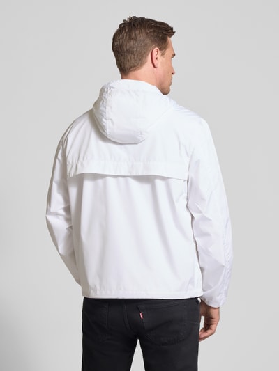 Męski model nosi Regular Fit Regenjacke mit Logo-Stitching von Polo Ralph Lauren, jednokolorowy, kaptur z tunelem, krój regular fit, długi rękaw, elastyczne zakończenie rękawów, tunelowe wykończenie dołu, boczne wpuszczane kieszenie, zamek błyskawiczny dwustronny, wyhaftowane logo, widok całej sylwetki z tyłu.