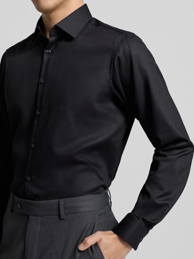Męski model nosi Regular Fit Business Hemd aus Baumwolle mit Kentkragen od Jake*s, czarna bawełna, krój regular fit, kołnierzyk kent, lista guzikowa, długość pleców w rozmiarze 39/40: 70 cm, szerokość ramion w rozmiarze 39/40: 47 cm, długość rękawa w rozmiarze 39/40: 64 cm, widok z przodu, zbliżenie na górną część ciała.