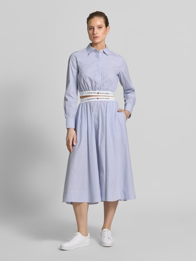 Frauenmodel trägt Ausgestellter Midi-Rock aus reiner Baumwolle von Tommy Hilfiger, wzór w paski, krój regular fit, rozkloszowana, długość midi, z napisem z logo, elastyczny ściągacz, wykończenie materiału: tkana faktura, bawełna, Ganzkörperansicht von vorne.
