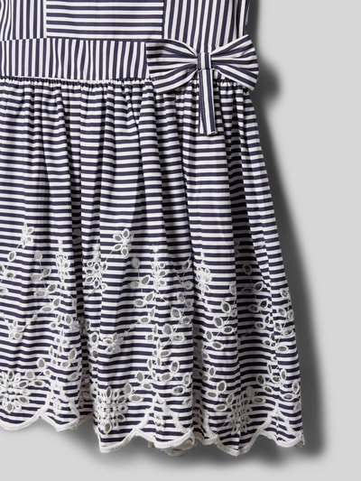 Mädchen trägt Regular Fit Kleid mit floralem Stitching von DANAMADE aus Reine Baumwolle, Lochmuster, Zierschleife, Nahaufnahme Unterteil.