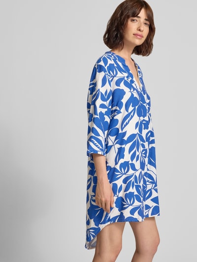 Frauenmodel trägt Minikleid aus Viskose-Mix mit verlängertem Rücken von ZABAIONE, blau-weiß gemustert, loose fit, Nahaufnahme Oberkörper. Damen Minikleid von ZABAIONE, Serafino-Kragen, 1/2-Arm, abgerundeter Saum, Rückenlänge 98 cm, Brustweite 57 cm, Ärmellänge 42 cm.