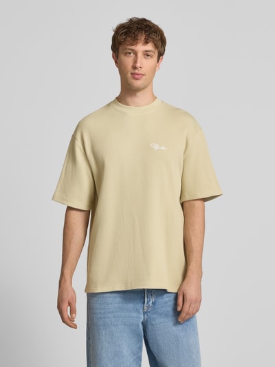 Männermodel trägt Oversized T-Shirt mit Strukturmuster von Pegador in Beige aus Baumwoll-Mix, Rundhalsausschnitt, Logo-Stitching, Ganzkörperansicht von vorne.