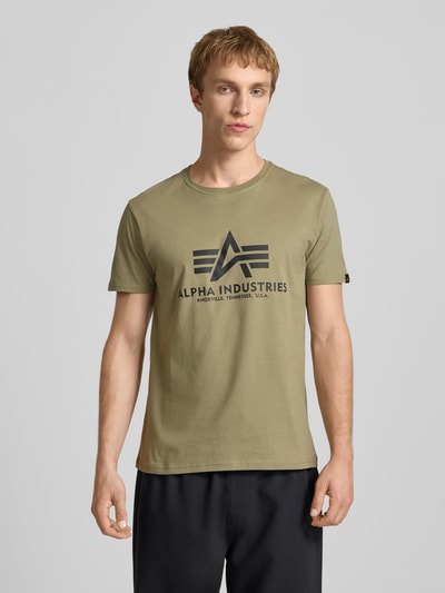 Männermodel trägt T-Shirt mit Logo und Rundhalsausschnitt von Alpha Industries in Olivgrün, reine Baumwolle, Regular Fit, Nahaufnahme Oberkörper.