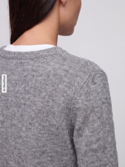 Frauenmodel trägt graue, melierte Regular Fit Strickjacke mit Woll-Anteil Modell 'MALOU' von PIECES, Nahaufnahme Rücken, KI-modifiziertes Bild.
