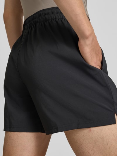 Männermodel trägt Regular Fit Sportshorts mit Logo-Print Modell 'TAD ESSENTIALS' von PUMA, schwarze Farbe, Herren Sportshorts, Nahaufnahme Rückansicht