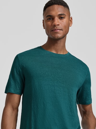 Männermodel trägt T-shirt aus leinen-elastaan-mix met ronde hals OLYMP Level Five, regular fit, labeldetail, ruglengte maat M 69 cm, nahaufnahme bovenlichaam.