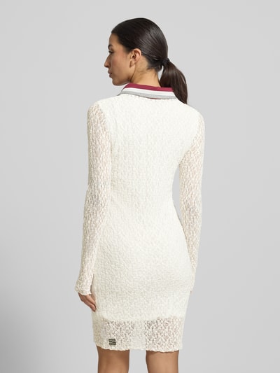 Frauenmodel trägt Slim Fit Kleid mit Polokragen von Marc Cain in Offwhite, semitransparente Spitze, knielang, Rückenansicht Ganzkörperansicht.