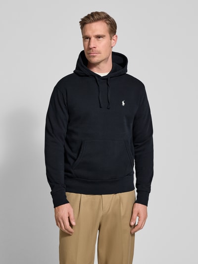 Mannenmodel draagt Relaxed Fit Hoodie aus reiner Baumwolle van Polo Ralph Lauren in effen zwart met logodetail, kangoeroezak, capuchon met tunnelkoord, lange mouwen met geribd boord, sweat van puur katoen. Ganzkörperansicht van voren.