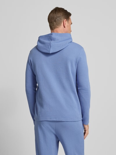 Männermodel trägt Comfort Fit Langarmshirt aus Baumwoll-Mix Modell 'WAFFLE' von BOSS in Hellblau, strukturierte Piqué-Optik, Kapuze, Ganzkörperansicht Rückansicht.