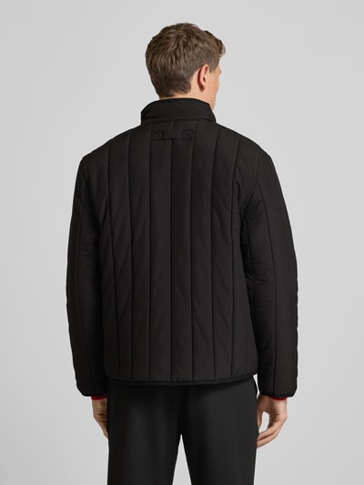 Männermodel trägt Regular Fit Steppjacke mit Stehkragen Modell 'BRENOTO' von HUGO, Optik: Unifarben, Ganzkörperansicht Rückansicht.