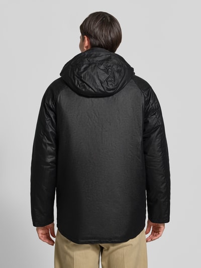 Männermodel trägt schwarzen Regular Fit Parka aus reiner Baumwolle von Barbour, matte Textur, Ganzkörperansicht Rückansicht.