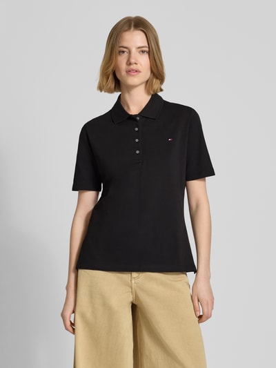 Frauenmodel trägt Regular Fit Poloshirts aus Baumwoll-Mix von Tommy Hilfiger in Schwarz, unifarben, mit Logo-Stitching und Polokragen, Piqué-Textur, Kurzarm, Ganzkörperansicht von vorne.