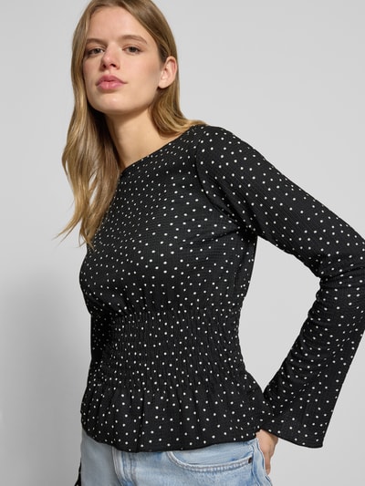 Frauenmodel trägt Longsleeve mit Rundhalsausschnitt von Gina Tricot, schwarzer Material-Mix mit weißen Punkten, Taillierter Schnitt, Smok-Details, Stretch-Anteil, Rückenlänge bei Größe S: 49 cm, Nahaufnahme Oberkörper.