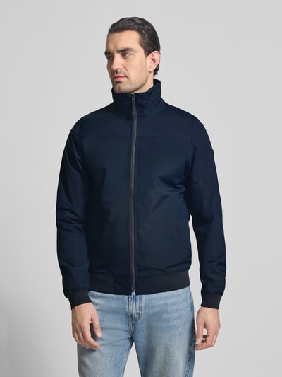 Mężczyzna nosi Regular Fit Kurtka ze stójką Model 'Alvin' od Didriksons, zamek błyskawiczny, elastyczne wykończenia, wpuszczane kieszenie, długość tyłu 69 cm, szerokość ramion 44 cm, szerokość w rozmiarze M 54 cm, długość rękawów 70 cm, widok całej sylwetki z przodu