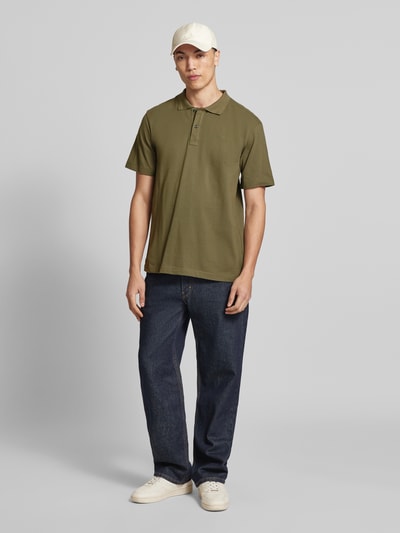 Männermodel trägt Regular Fit Poloshirt aus reiner Baumwolle Modell 'Core' von G-Star Raw in Olivgrün, Ganzkörperansicht von vorne.