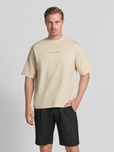 Männermodel trägt Relaxed Fit T-Shirt aus reiner Baumwolle Modell 'NORMAN' von Selected Homme, cremefarben, Herren T-Shirt, Ganzkörperansicht von vorne.