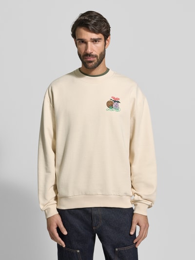 Męski model ma na sobie Sweatshirt mit Label-Print und Rundhalsausschnitt od Les Deux, beżowy kolor, bawełna, cała sylwetka z przodu, relaxed fit.