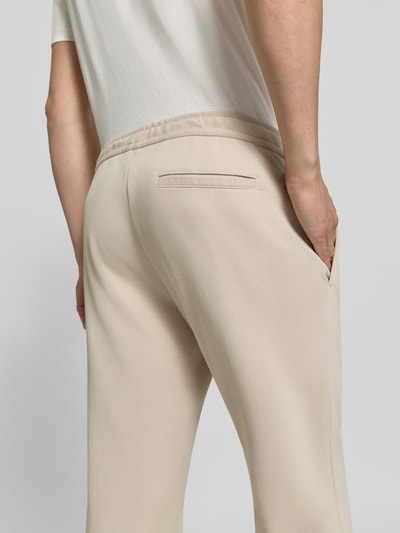 Männermodel trägt Straight Fit Hose mit Baumwoll-Anteil Modell 'Parker' von MCNEAL in Beige, Gesäßtasche, elastischer Bund, Nahaufnahme Rückansicht. Material-Mix, Innenbeinlänge bei Größe M 73 cm.
