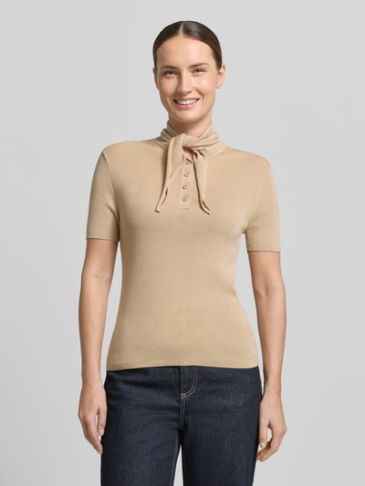 Frauenmodel trägt Modern Fit Poloshirt mit Seiden-Anteil und Schluppe von Stefanel in Beige, glatte Textur, feiner Lyocell-Mix, kurze Knopfleiste, Ganzkörperansicht von vorne.