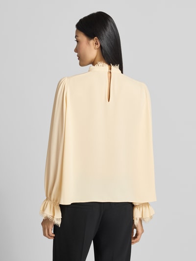 Frauenmodel trägt Regular Fit Bluse mit Spitzenbesatz von Marc Cain in Creme, lockerer Schnitt, Chiffon, Stehkragen, Ganzkörperansicht Rückansicht.