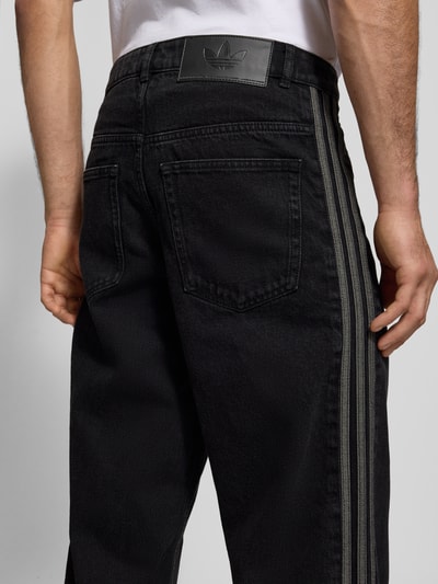 Männermodel trägt Jeans mit Eingrifftaschen von adidas Originals in Schwarz, Reine Baumwolle, Regular-Fit, Detailaufnahme Rückansicht.