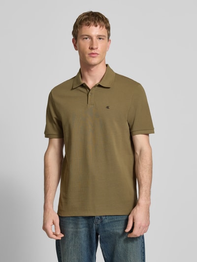 Männermodel trägt Straight Fit Poloshirt mit Label-Stitching von Calvin Klein Jeans aus reiner Baumwolle, Polokragen, olivgrün, Nahaufnahme Oberkörper.