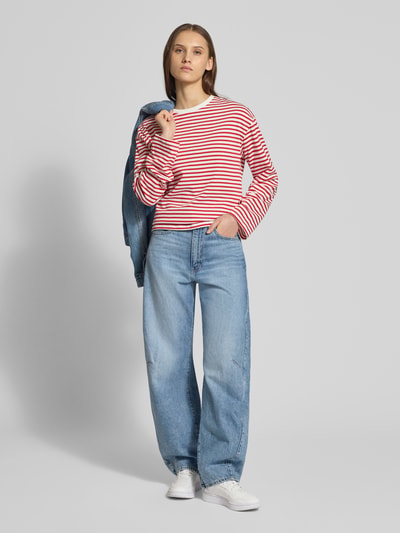 Modelka nosi Regular Fit Langarmshirt aus Baumwoll-Mix Modell 'SADIE' od Pieces, czerwono-białe paski, okrągły dekolt, długi rękaw, bawełniany miks, całe ciało z przodu.