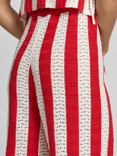 Frauenmodel trägt Strickhose mit Label-Detail und elastischem Bund von Karo Kauer im Baumwoll-Mix, rot-weiß gestreift, Detailaufnahme.