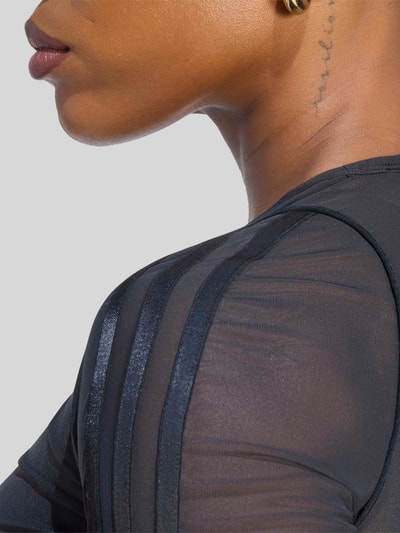 Vrouwenmodel draagt Regular Fit Sport-Langarmshirt met Logo-Detail van adidas Training, unikleuren, mat mesh, spitse patroon, ronde hals, lange mouwen met rolzoom, logo-applicatie, detailopname schouder.