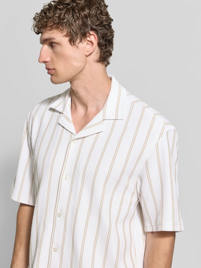 Männermodel trägt Relaxed Fit Kurzarmhemd aus Baumwoll-Mix von BOSS mit Allover-Muster, Reverskragen, creme und beige, Nahaufnahme Oberkörper.